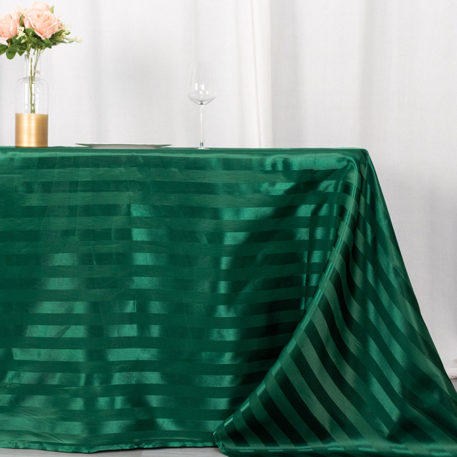Emerald green satin stripe rectangular tablecloth on a dining table.