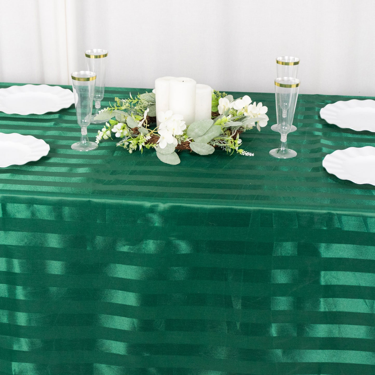 Emerald green satin stripe tablecloth on a dining table with decor.