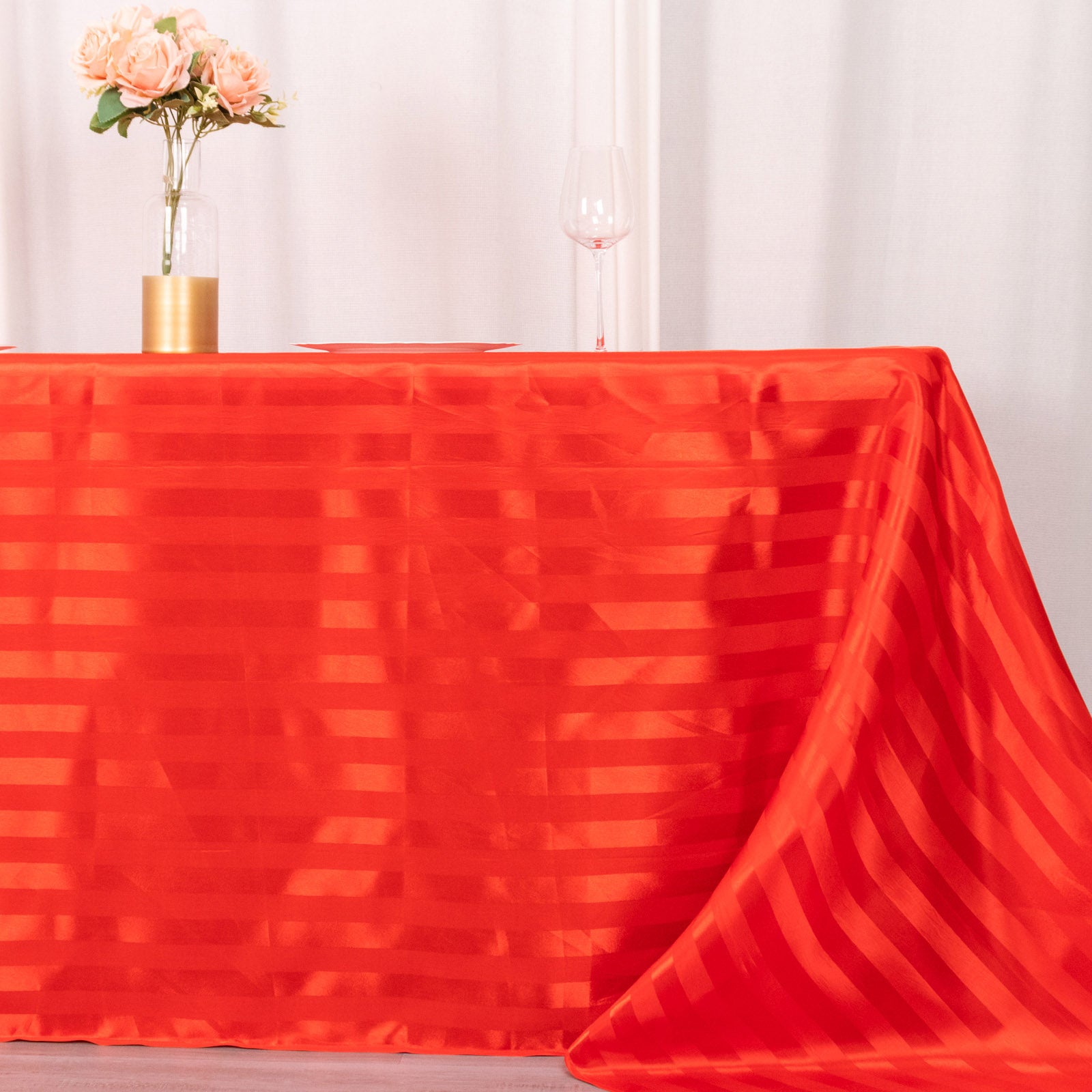 Red satin stripe rectangular tablecloth on a dining table.