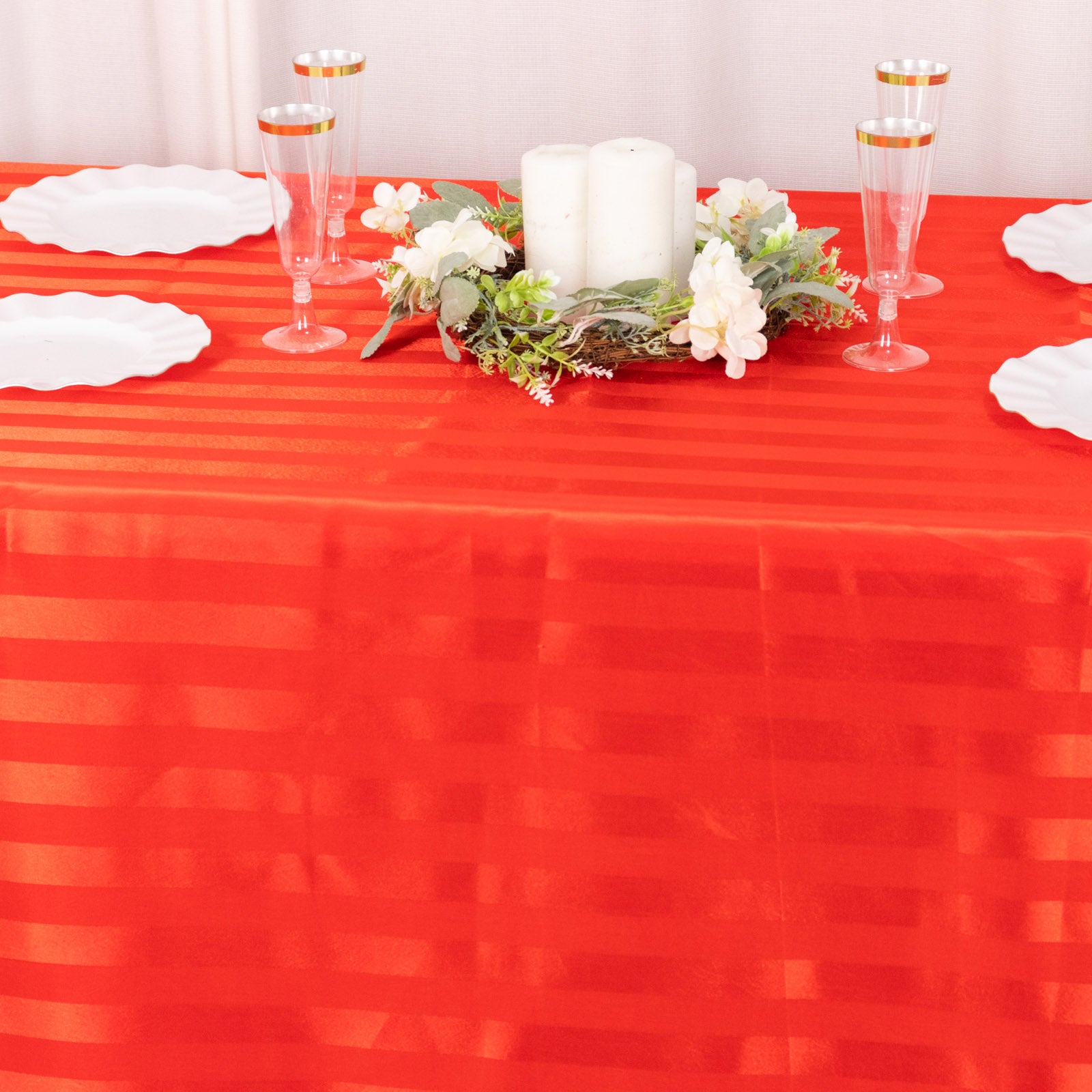 Red satin stripe rectangular tablecloth on a decorated table.