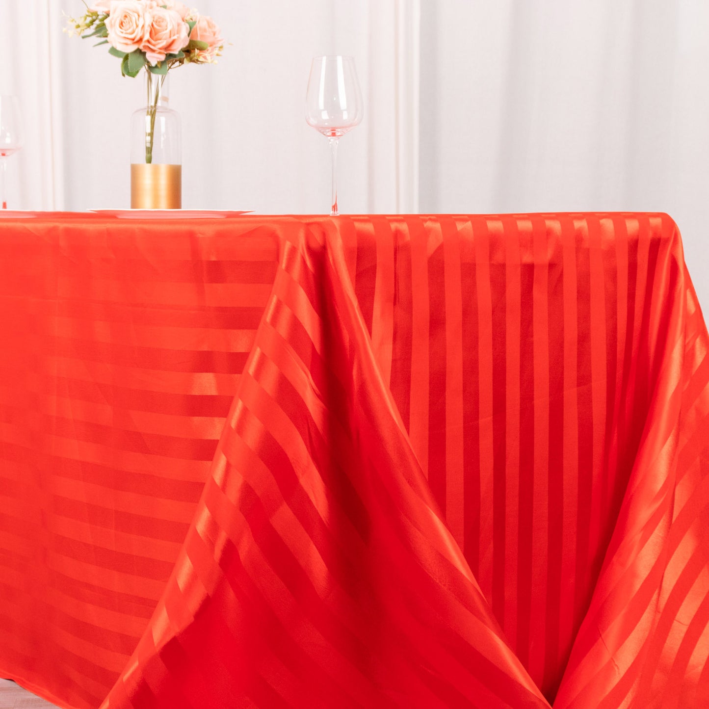 Red satin stripe rectangular tablecloth on a decorated table.