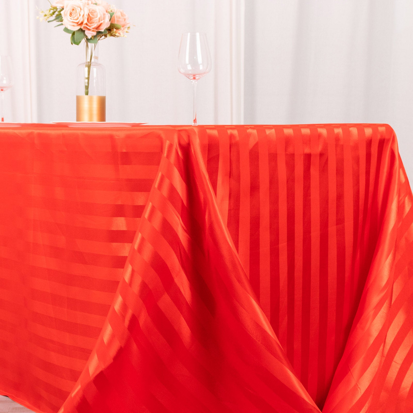Red satin stripe rectangular tablecloth on a decorated table.