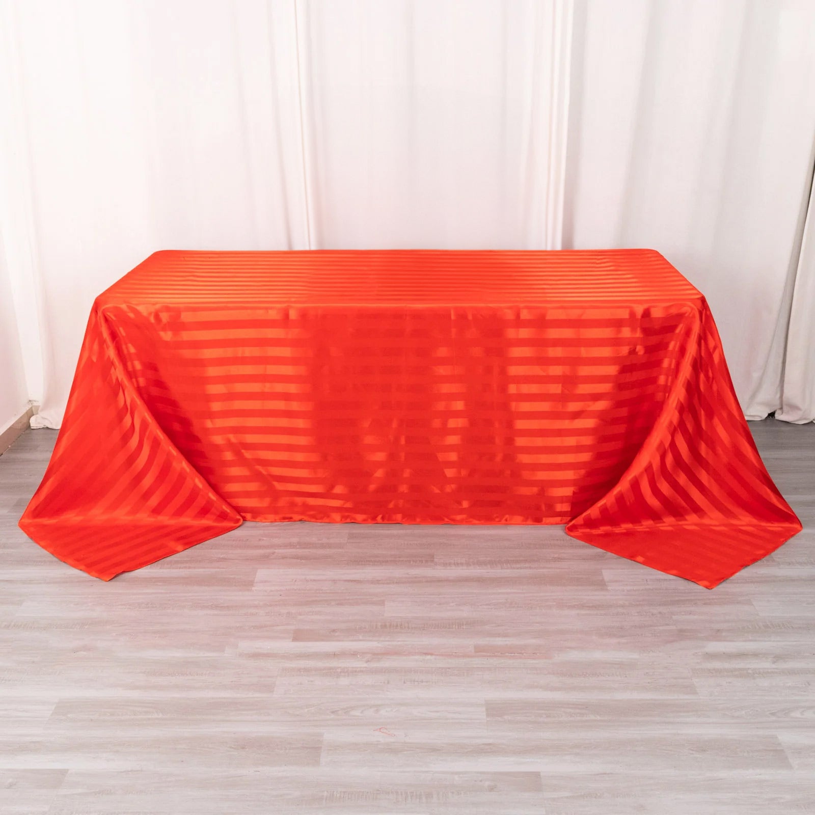 Red satin stripe rectangular tablecloth on a wooden surface.