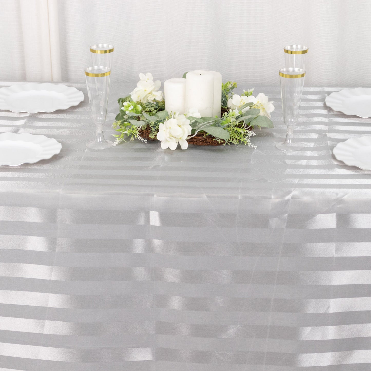 Silver satin stripe tablecloth on a dining table with decor.