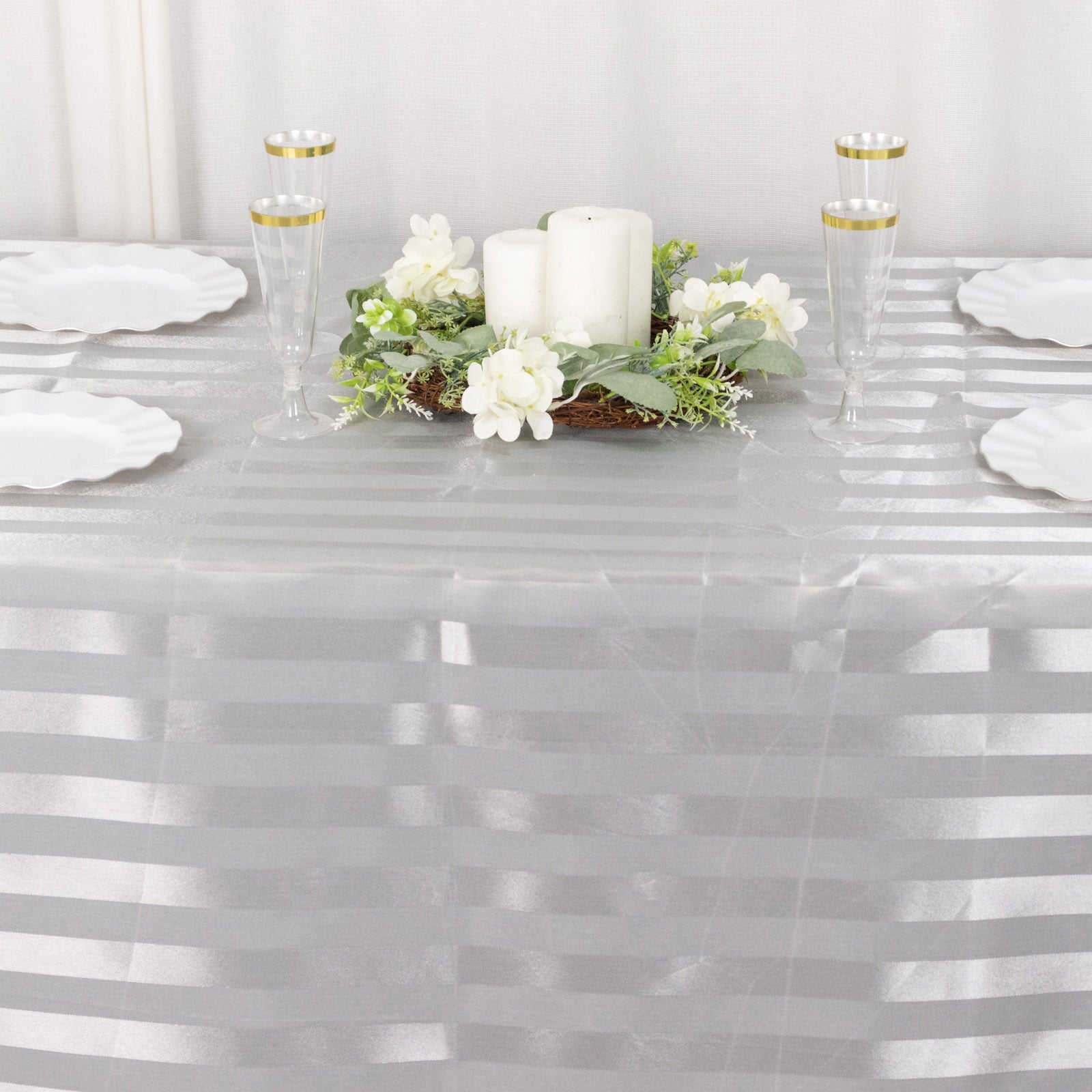 Silver satin stripe tablecloth on a dining table with decor.