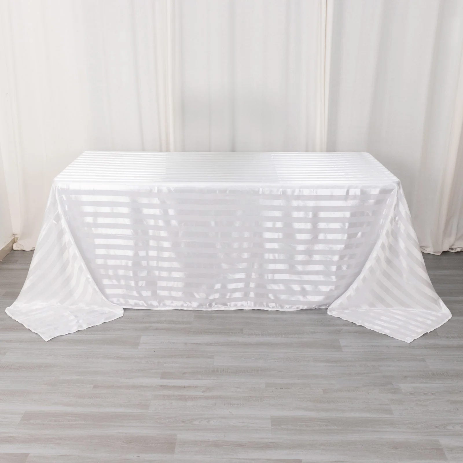 White satin stripe tablecloth on a rectangular table.