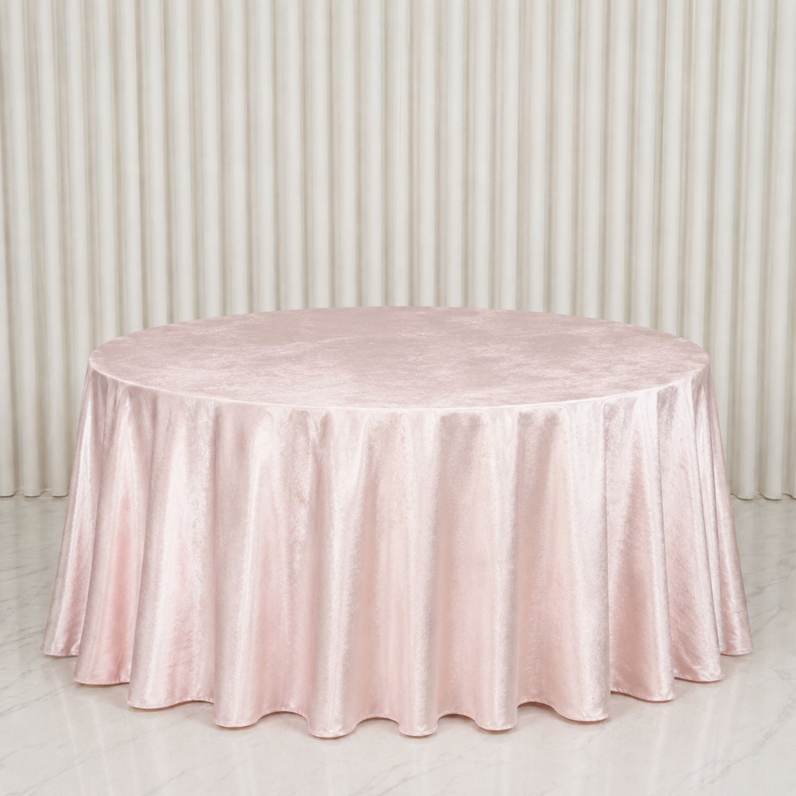 Blush round velvet tablecloth on a marble surface.