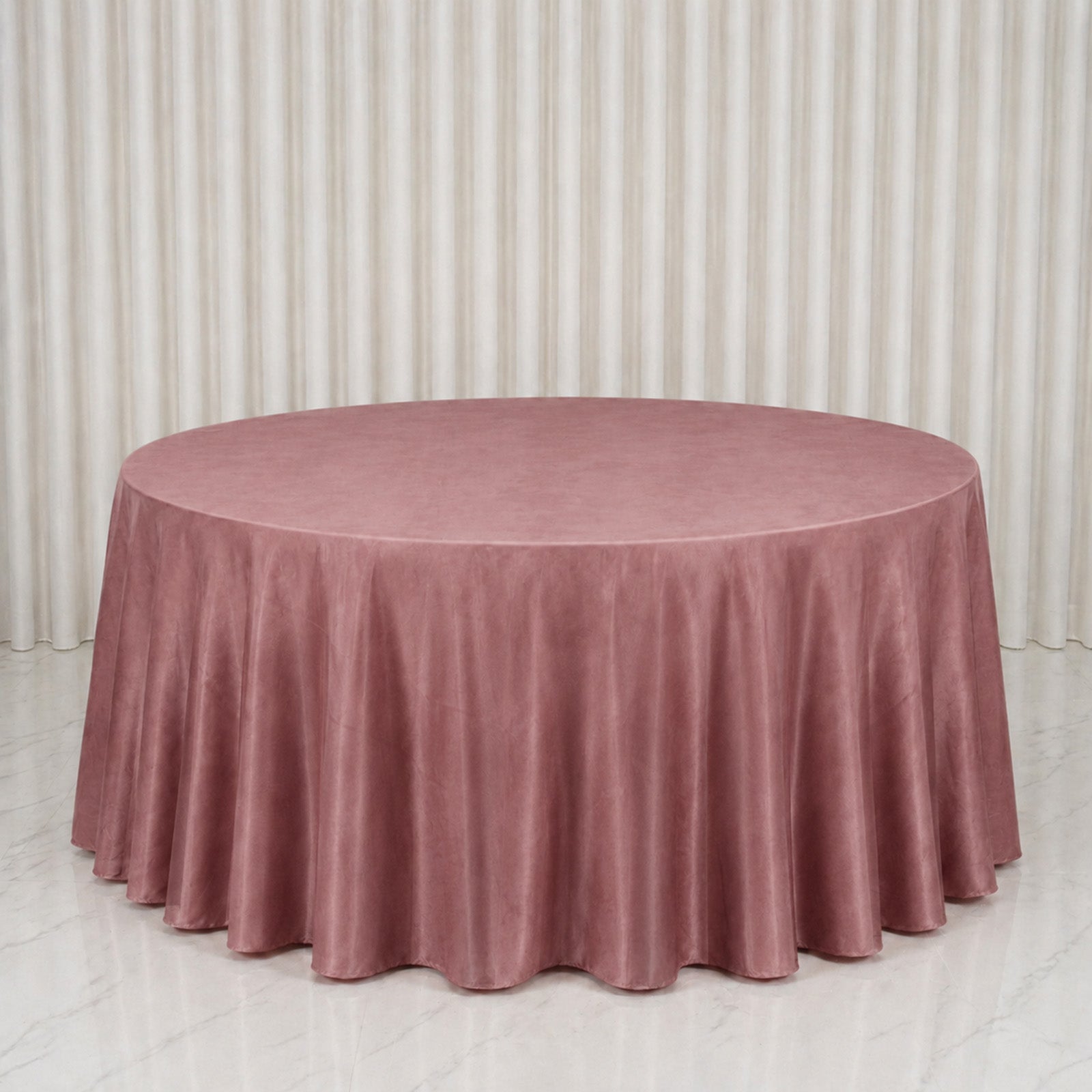 Dusty rose round velvet tablecloth on a marble surface.
