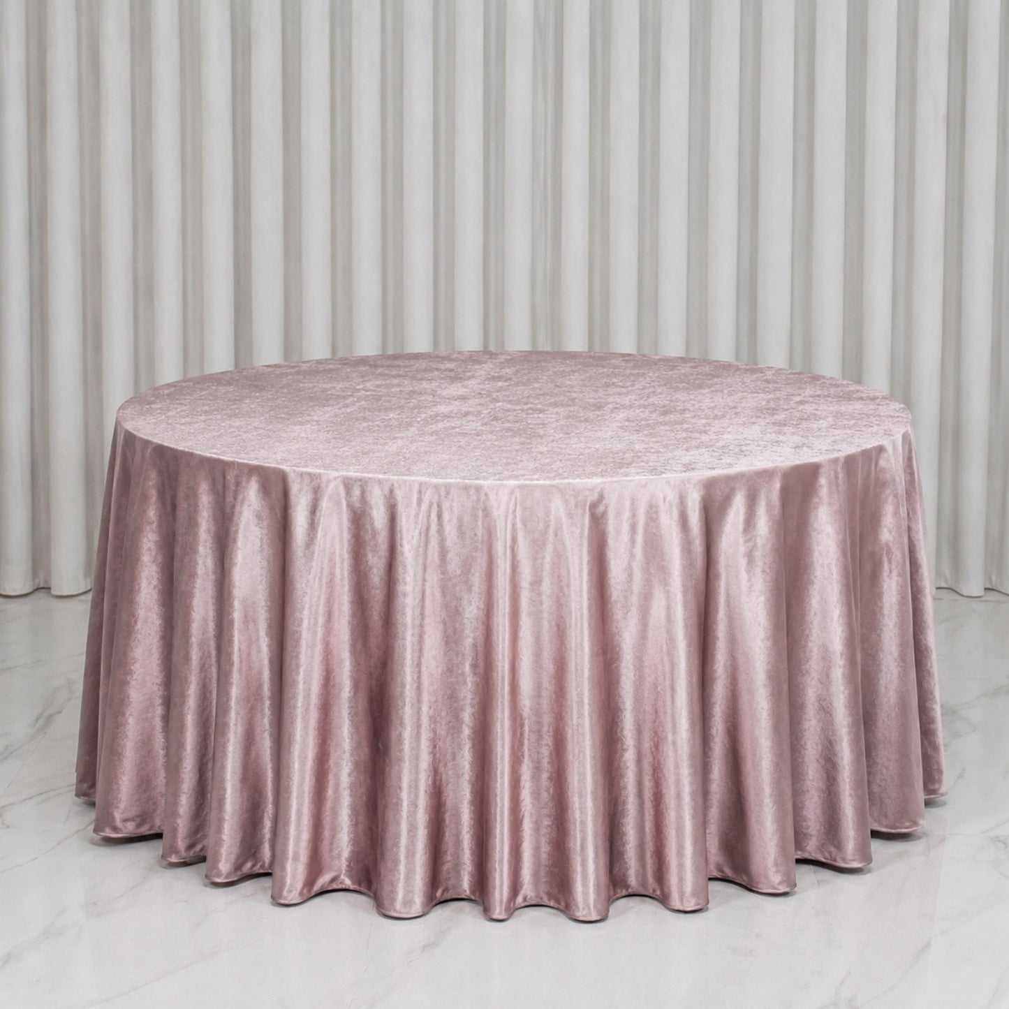 Mauve round tablecloth on a smooth surface with pleated edges.