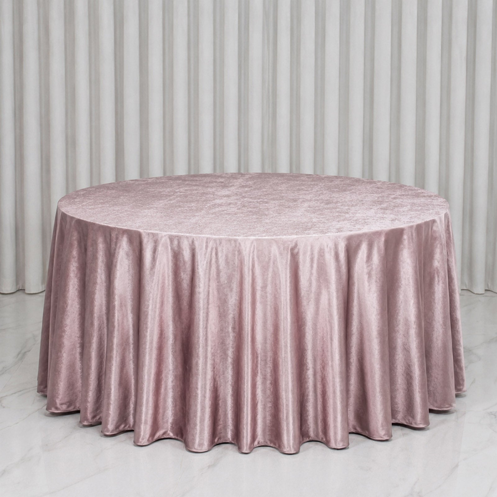Mauve round tablecloth on a smooth surface with pleated edges.