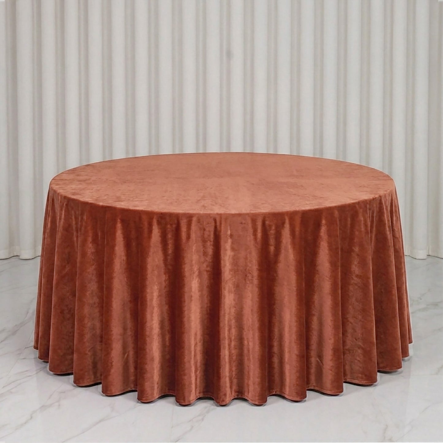 Terracotta round velvet tablecloth on a marble surface.