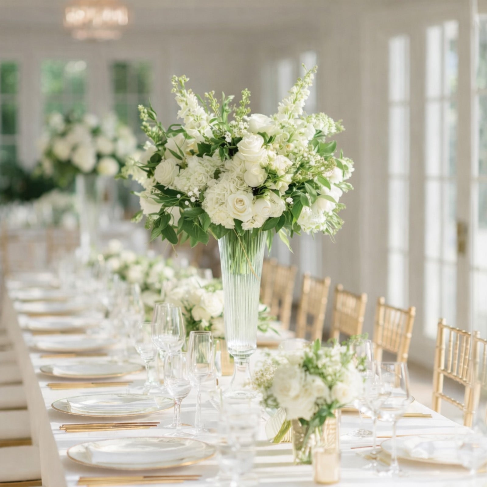 Clear ribbed glass trumpet vase with white floral centerpiece.