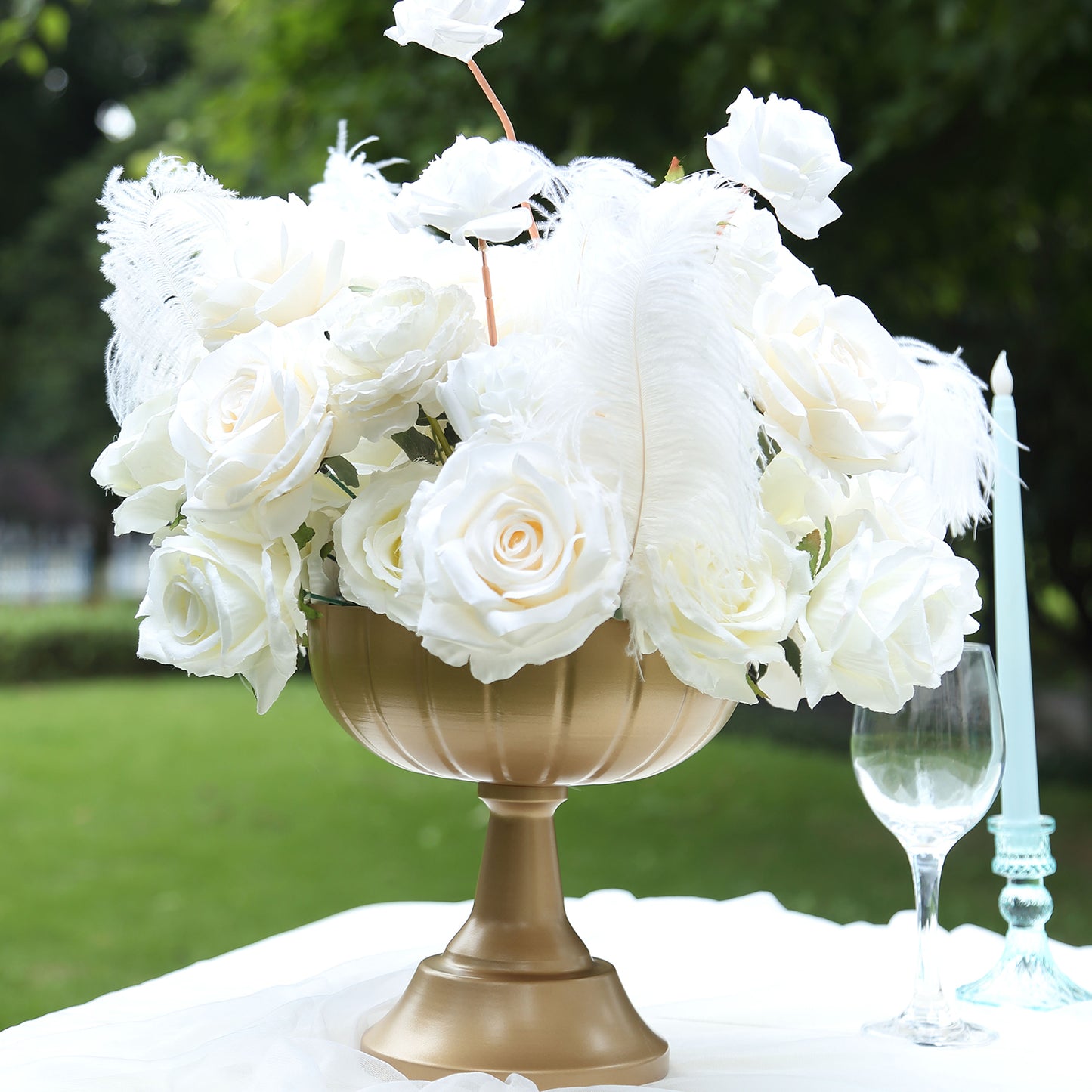 Gold compote pedestal bowl vase with white roses and feathers, decorative centerpiece.