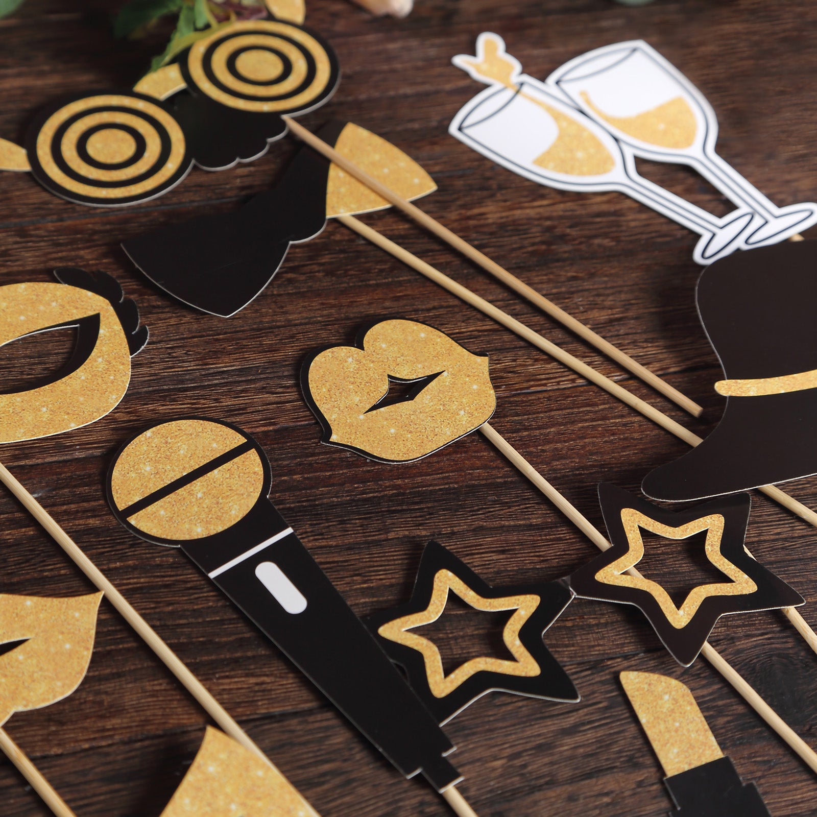 Vintage black and gold glitter party photo booth props on wooden surface.