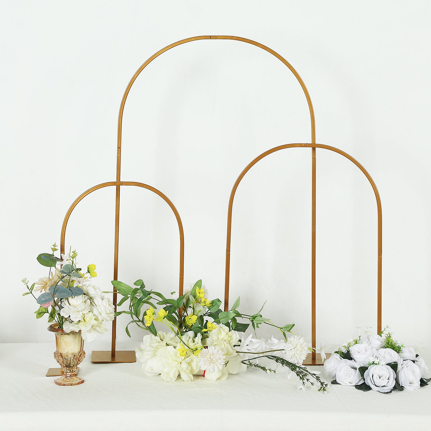 Gold metal chiara arch wedding cake display stand with floral arrangements.