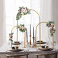 Gold metal wedding cake display stand with floral arrangements and rounded tops.