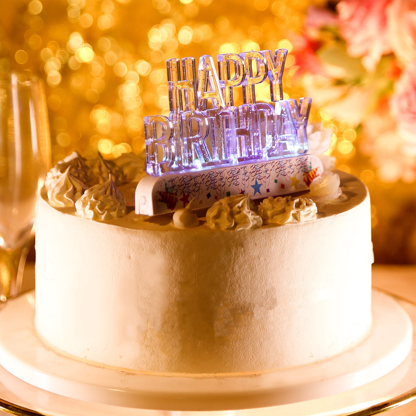 Clear acrylic multicolor flashing LED birthday cake topper on a white cake.