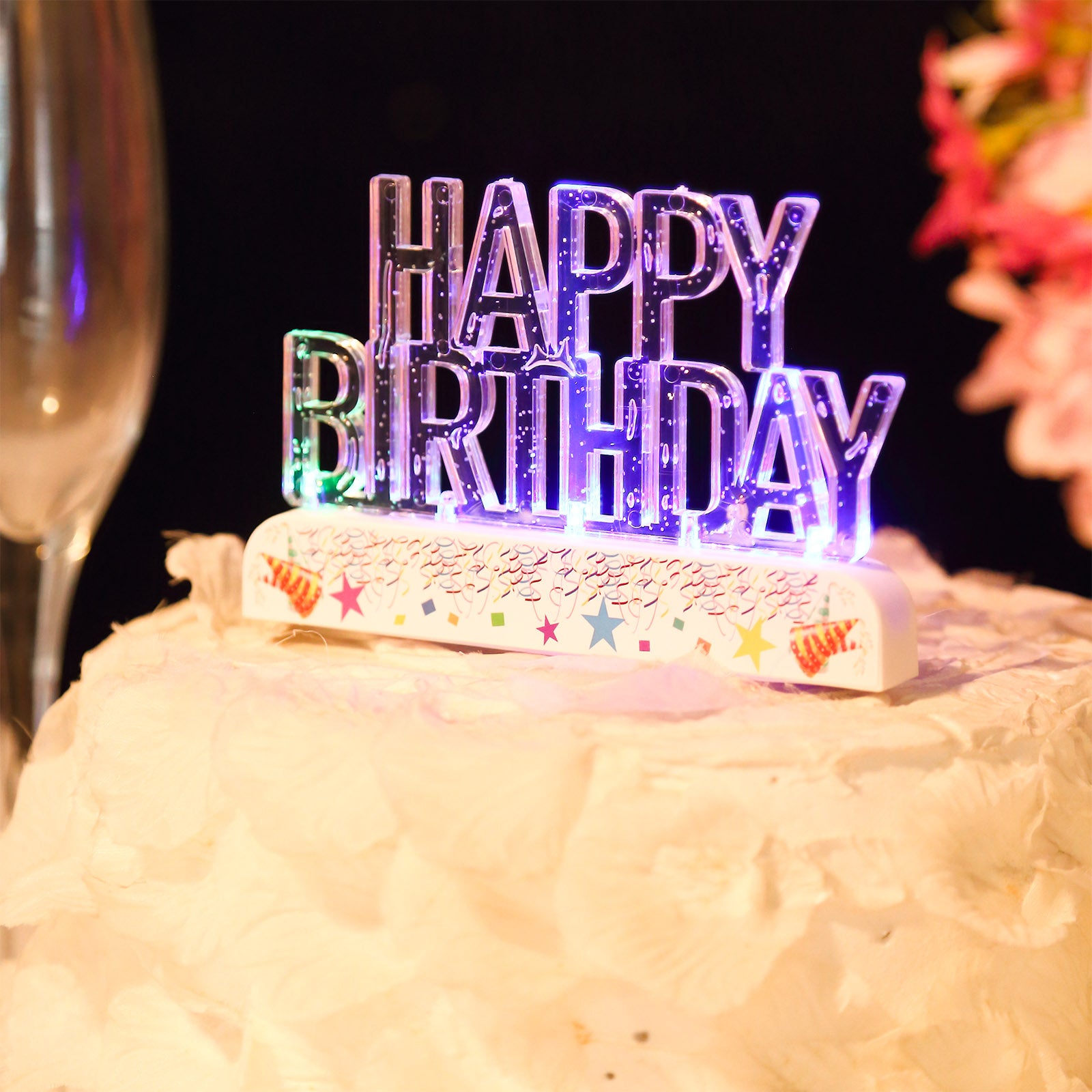 Clear acrylic multicolor LED Happy Birthday cake topper on a white cake.