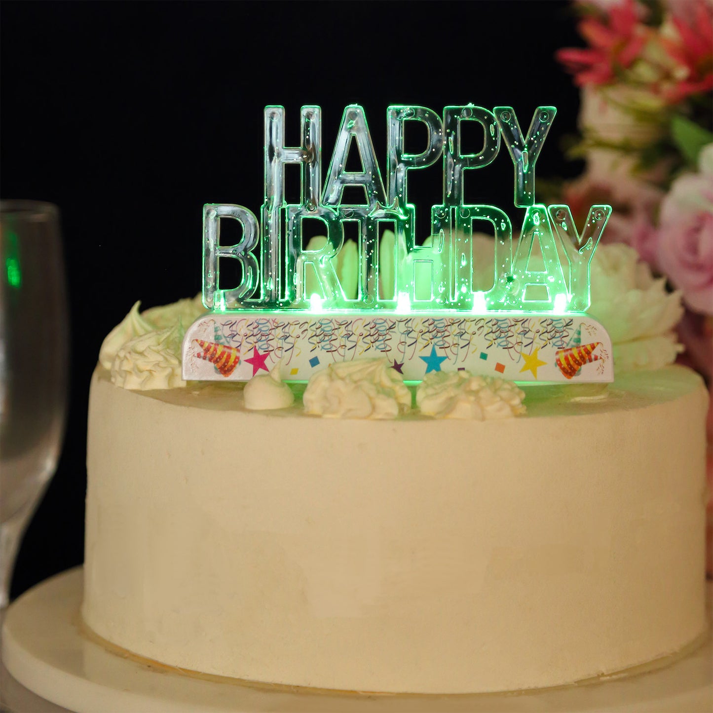 Clear acrylic multicolor flashing LED birthday cake topper on a white cake.