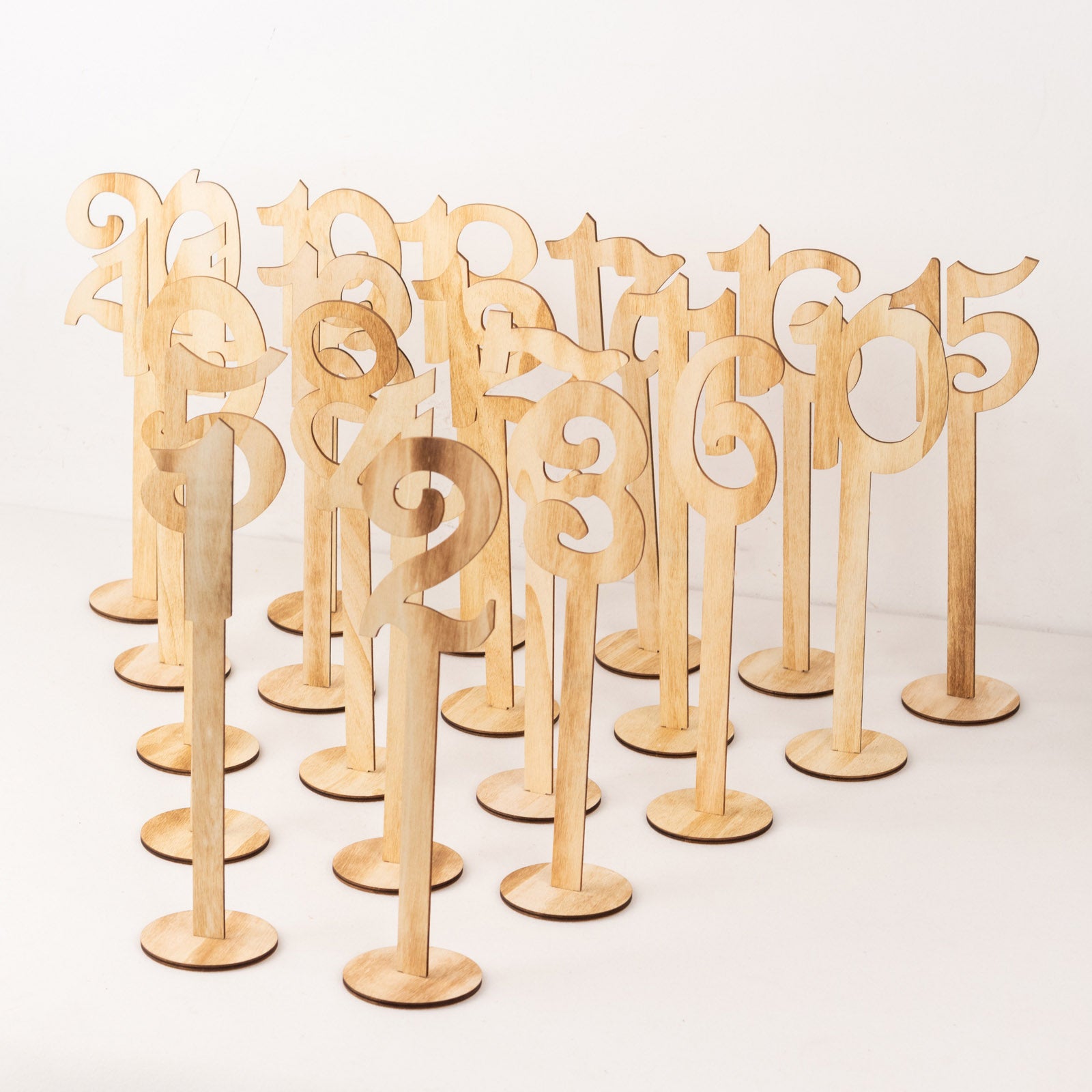 Natural wooden wedding table numbers set on sticks with round bases.