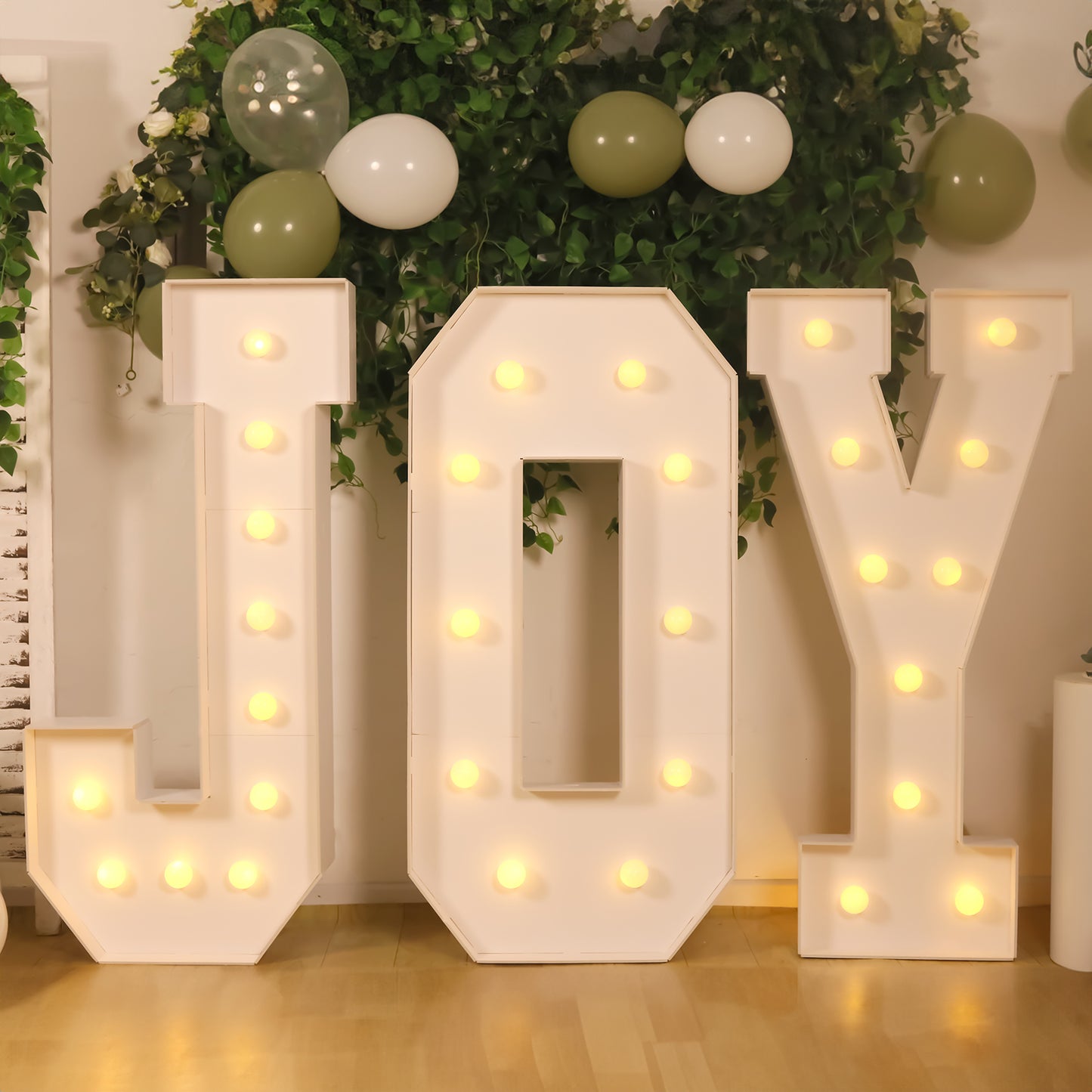 White LED marquee letters "JOY" with warm white lights.