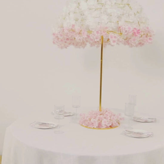 Gold floral umbrella stand centerpiece with pink flowers on a round table.