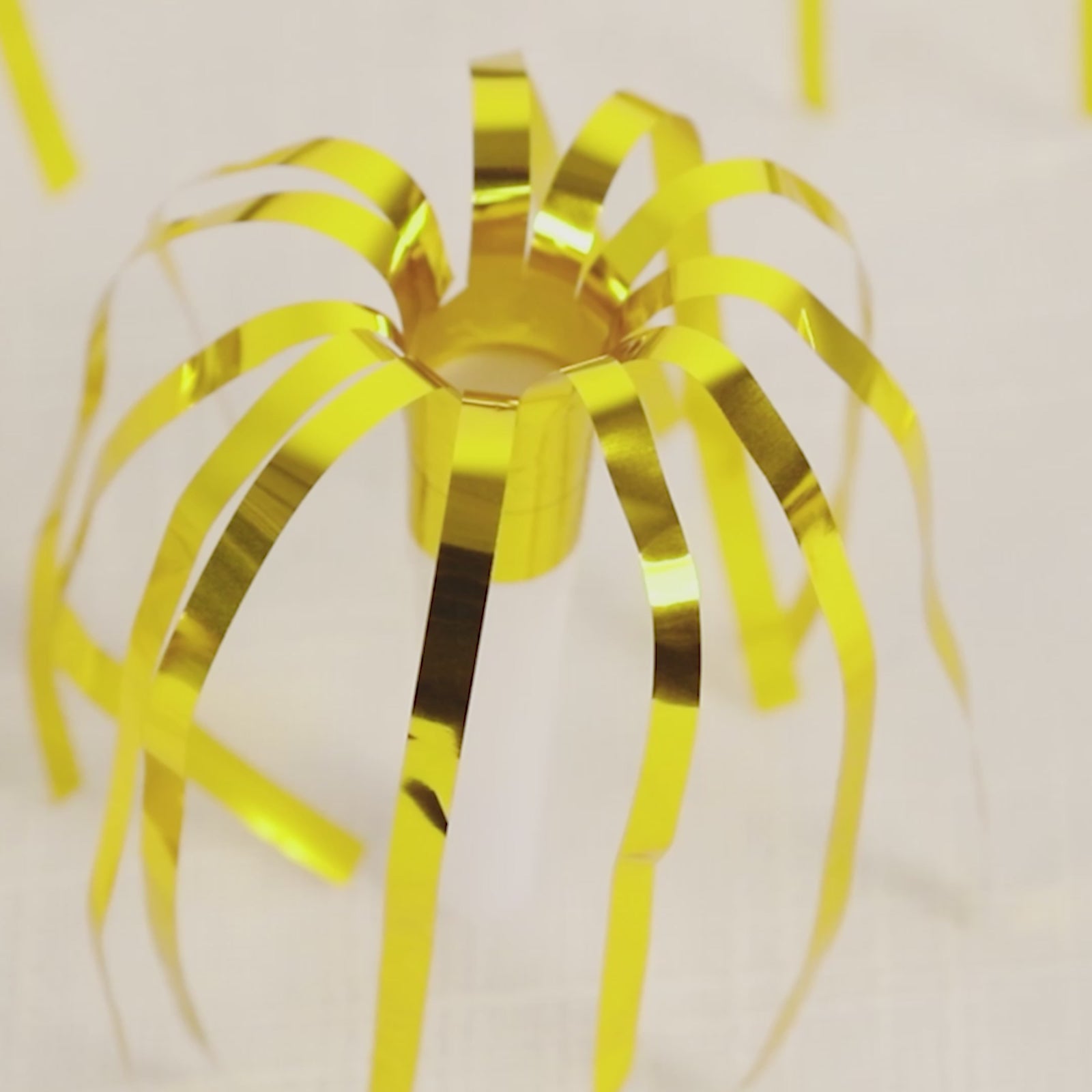 Gold metallic party horn noisemaker with tassels for celebrations.