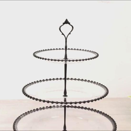 Clear 3-tier dessert display stand with black beaded rim and handle.