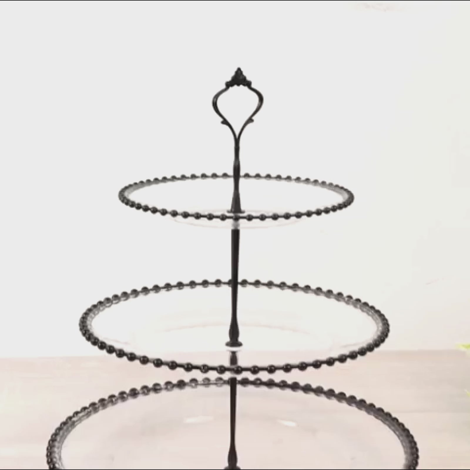 Clear 3-tier dessert display stand with black beaded rim and handle.