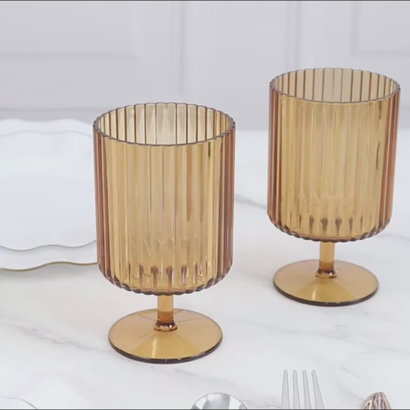 Amber gold vintage ribbed pattern plastic goblets on a marble surface.