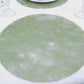 Olive green round disposable placemat on a dining table.