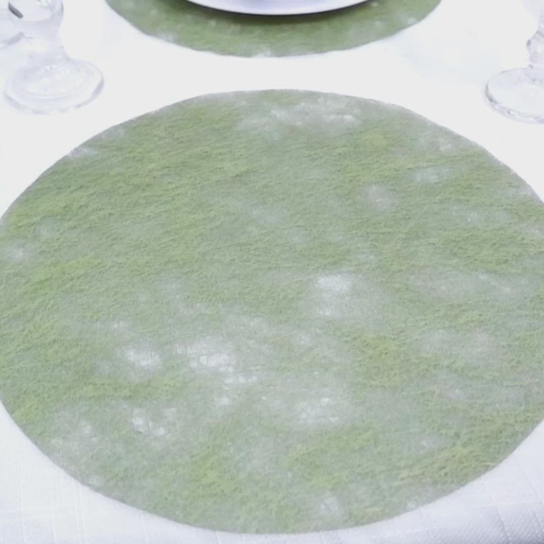 Olive green round disposable placemat on a dining table.