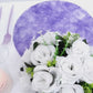Lavender lilac round placemat with white floral arrangement on a table.