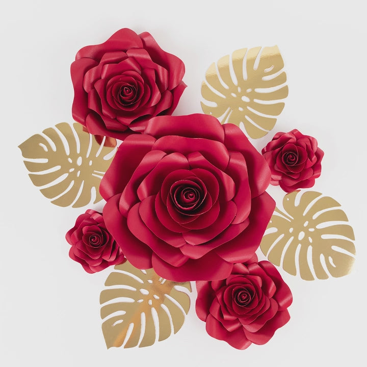 Set of red 3D rose paper flowers with gold palm leaves for wall decor.