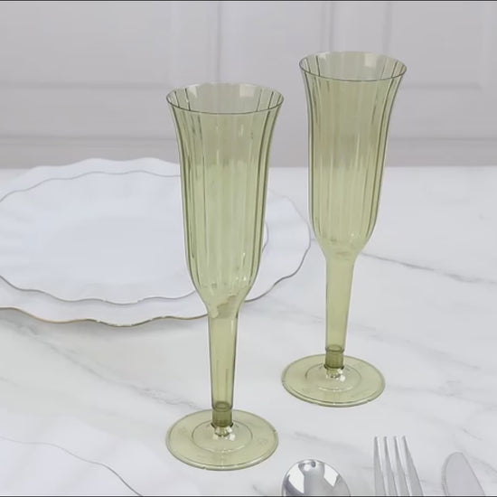 Dusty sage green disposable champagne flutes on a marble surface.