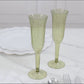 Dusty sage green disposable champagne flutes on a marble surface.