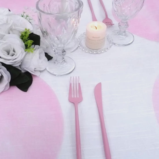 Pink disposable placemats on a dining table with glassware and flowers.