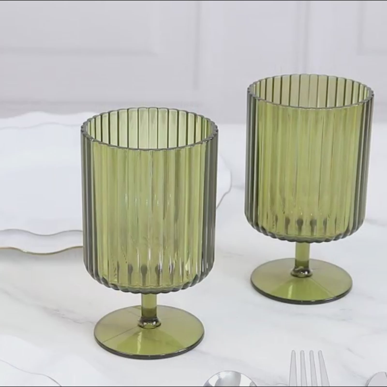 Dusty sage green vintage ribbed short stem goblets on a marble surface.