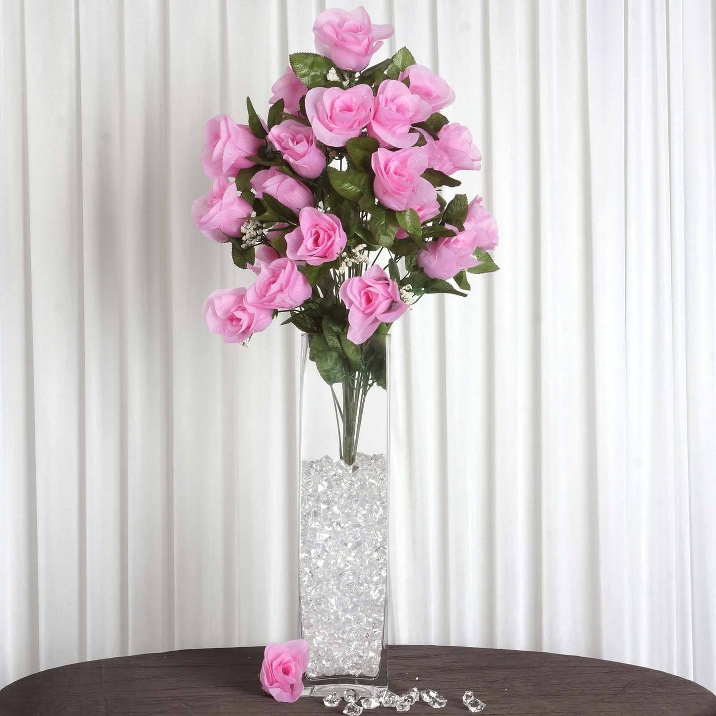 25" Long stem pink artificial silk rose bud flowers in a clear vase.