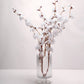 White artificial silk carnation flower stems in a clear glass vase.