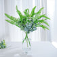 Artificial green cycas fern leaves in a clear vase.