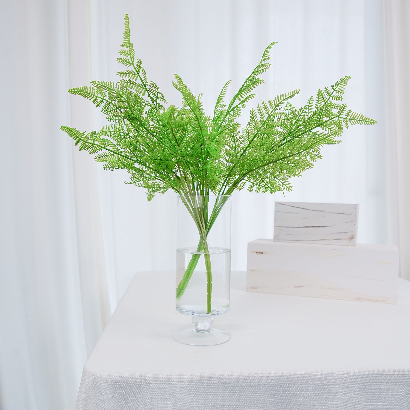 Green artificial asparagus fern leaf plant in a vase.