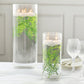 Green artificial fern leaves in vases with floating candles.