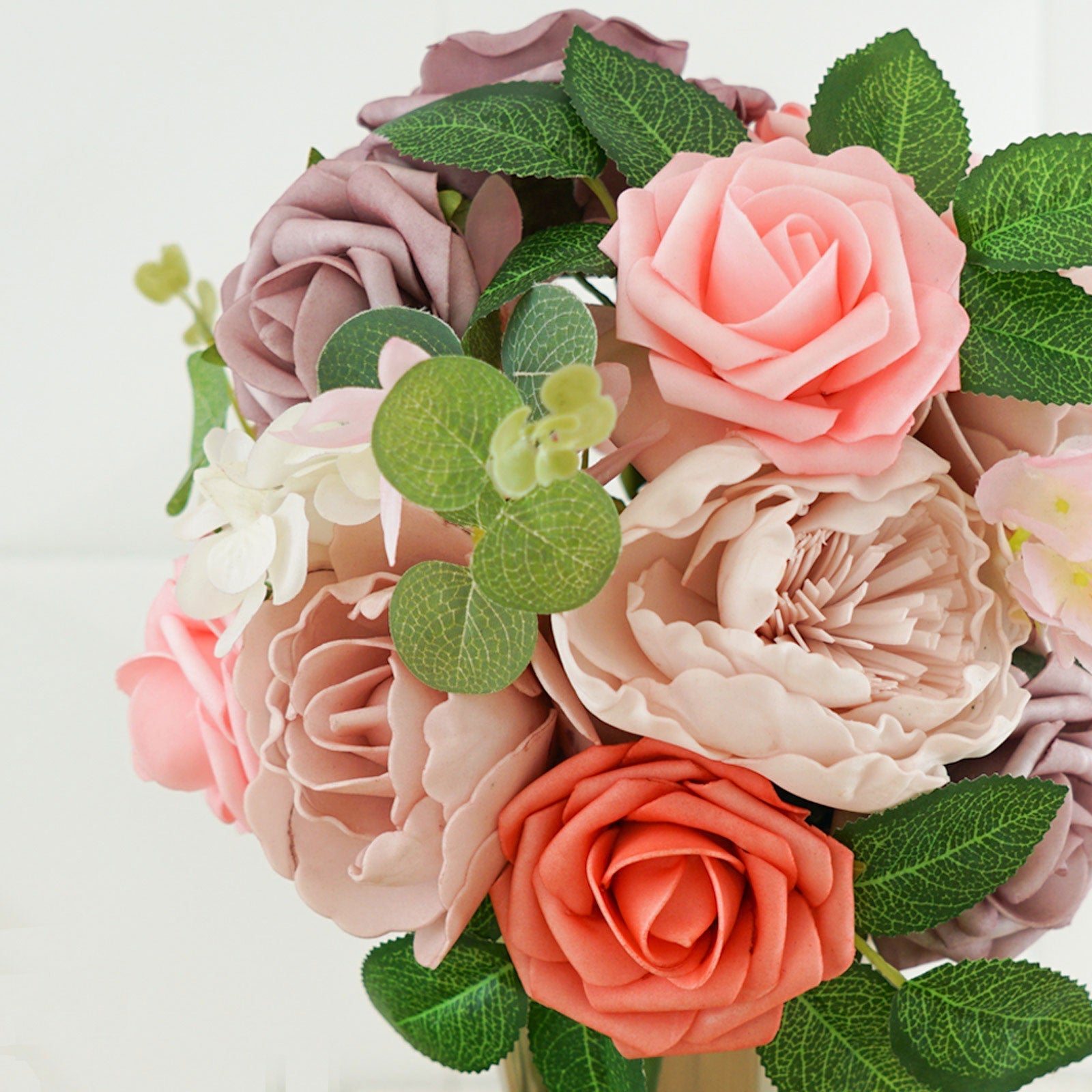 Assorted pink and peach artificial flower bouquet with greenery.