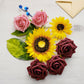 Burgundy and pink artificial roses with yellow sunflowers and blueberries.