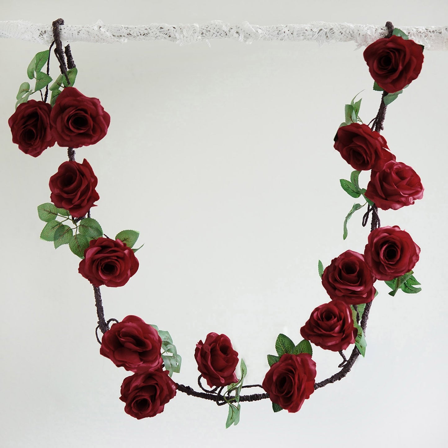 Burgundy artificial silk rose hanging flower garland with greenery.