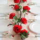 Red artificial silk rose garland for elegant table decor.
