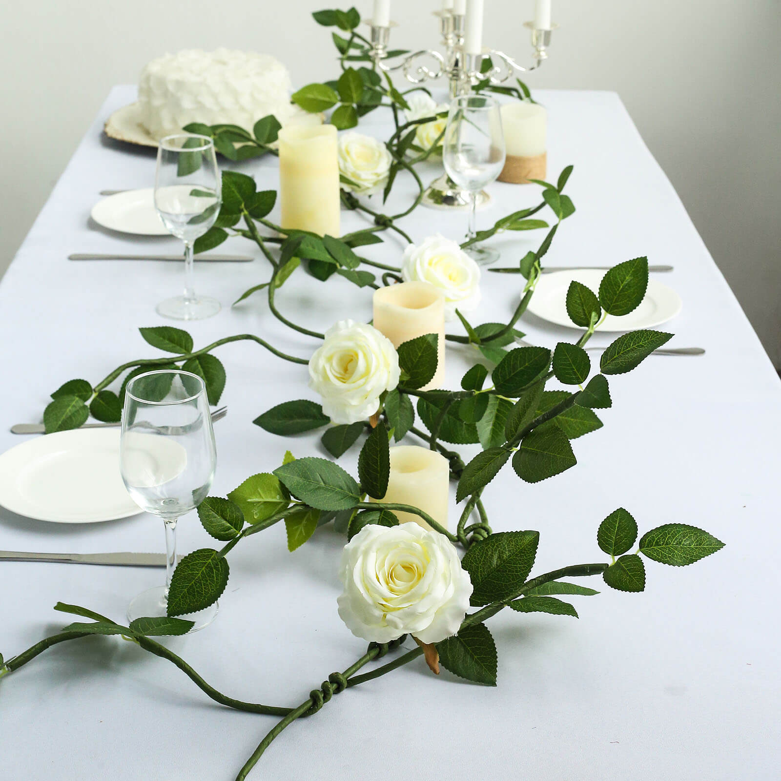 Cream artificial rose and leaf flower garland vine for elegant table decor.