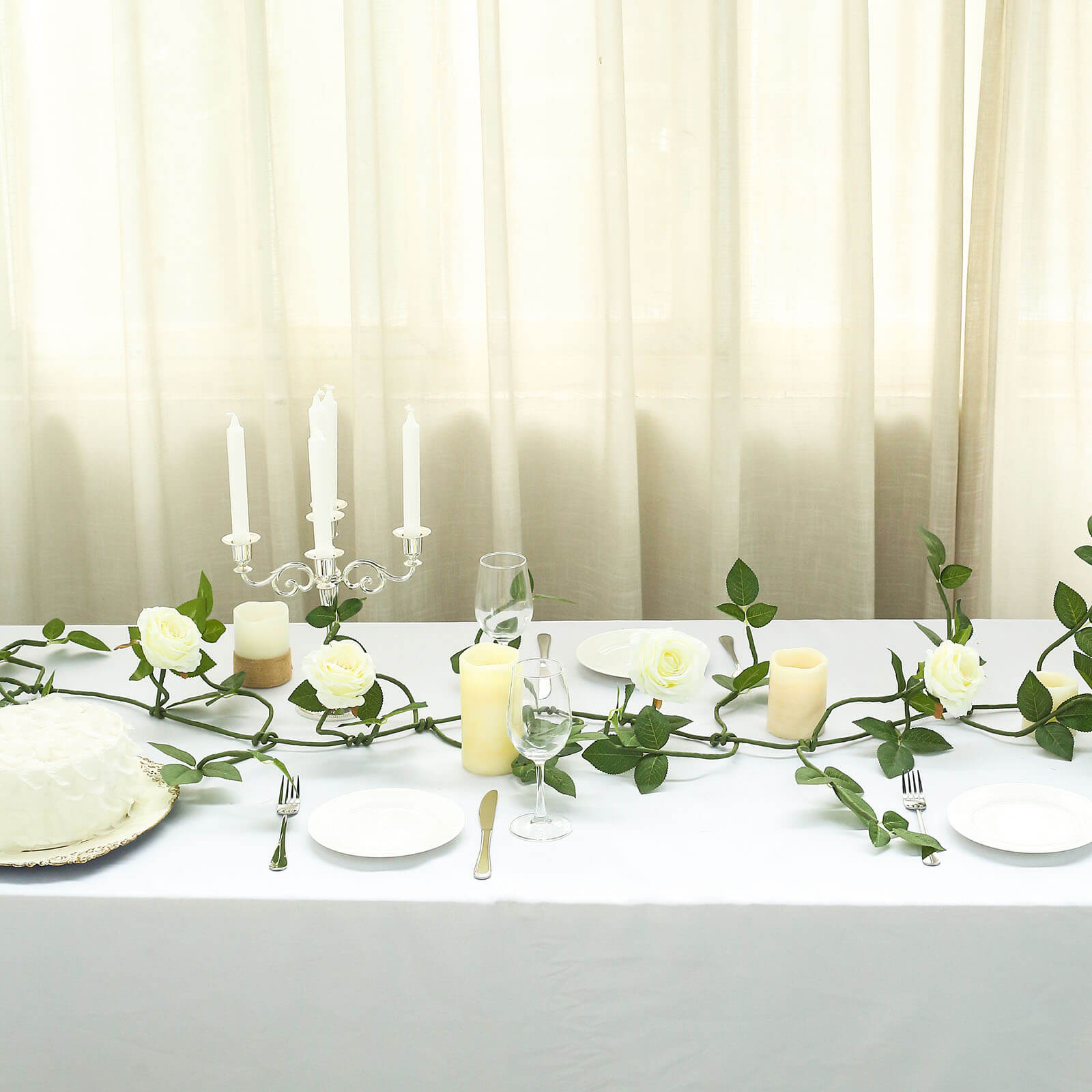 Cream artificial rose and leaf flower garland vine on a dining table.