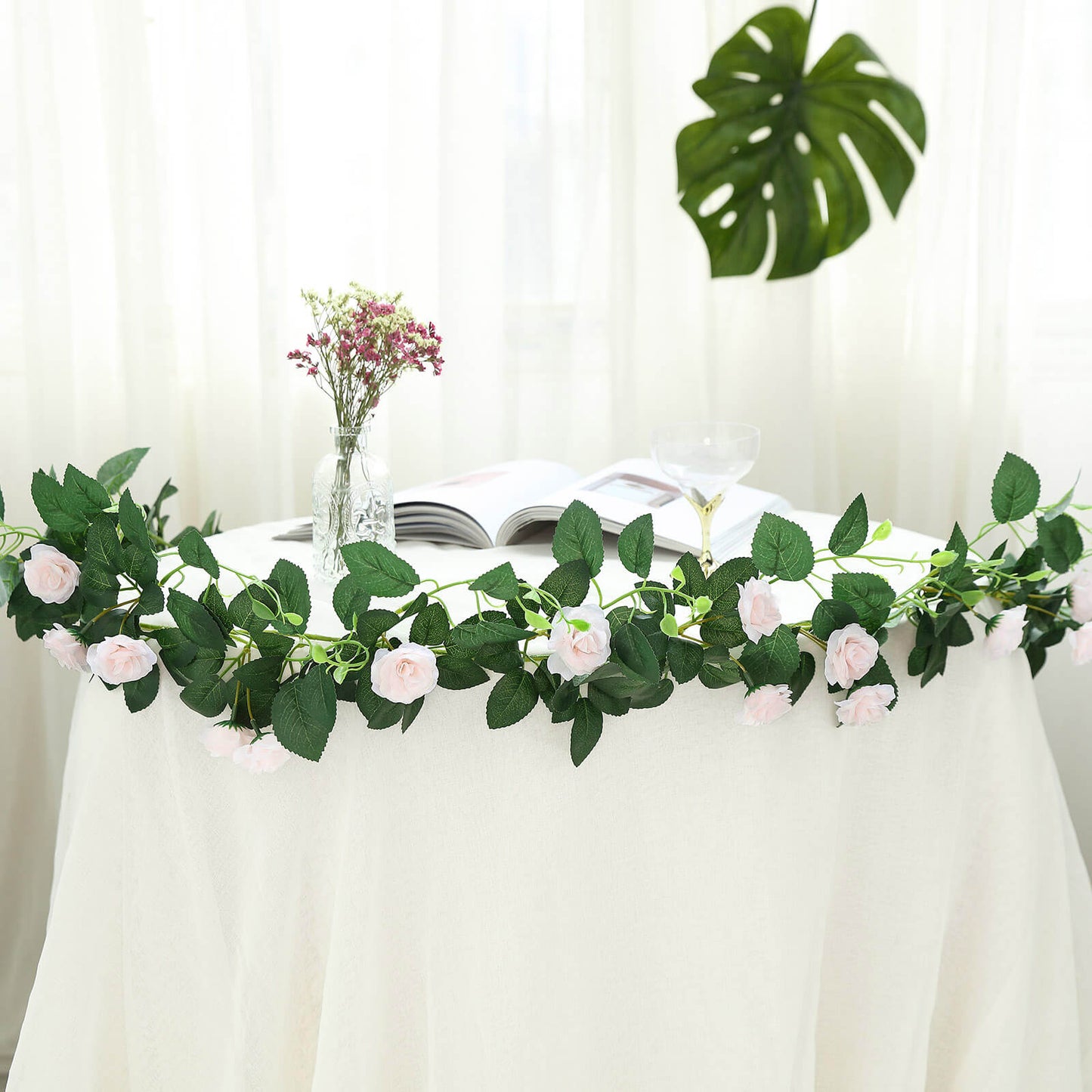 Blush artificial silk roses flower garland vine on a table.